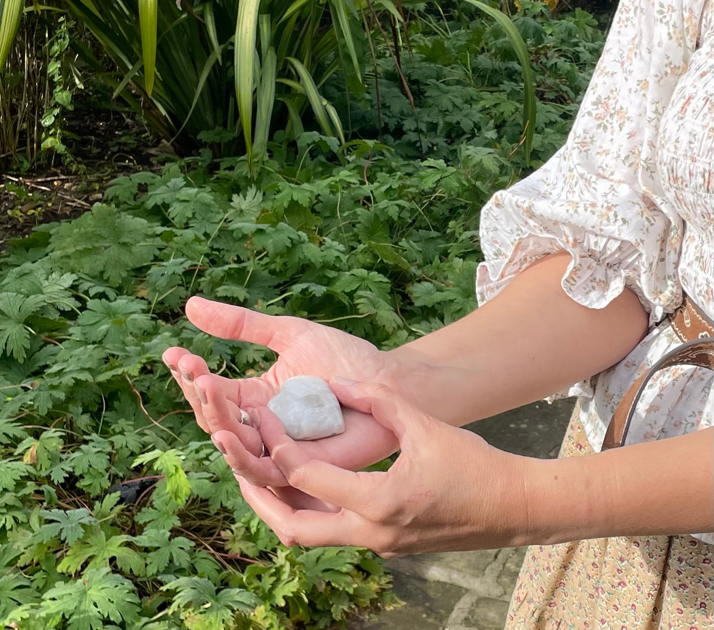 Polished white moonstone heart crystal in models hand with red hair and frilly top