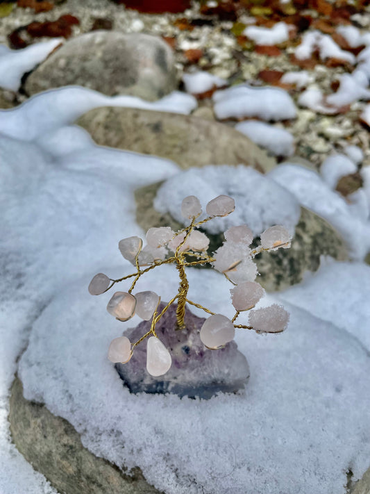 Rose quartz and amethyst crystal tree photographed in the snow