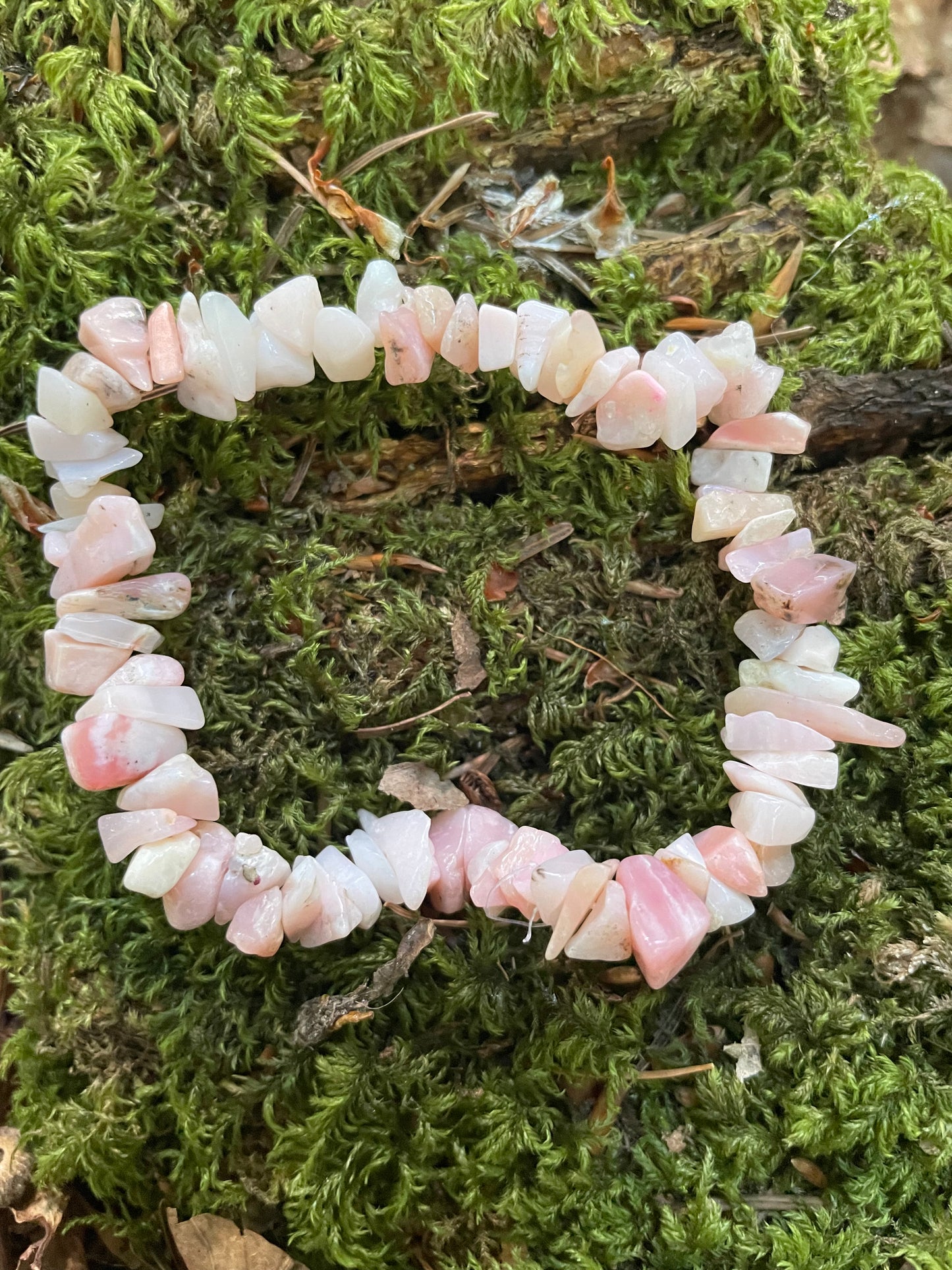 Pretty pastel pink crystal chip elasticated bracelet shown on green moss in the woods