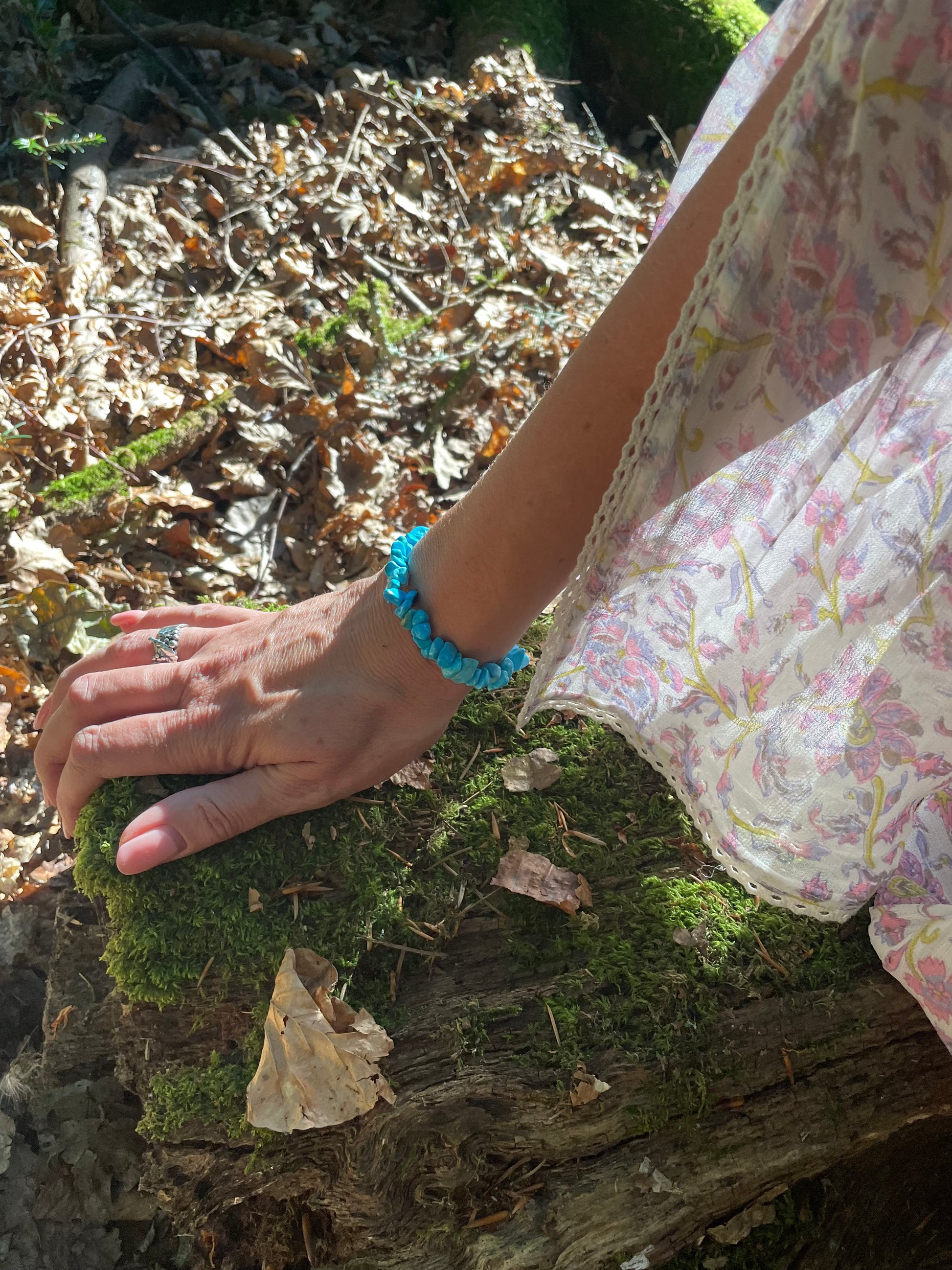 Deep turquoise crystal chip elasticated bracelet. It is shown on models arm in the woods. You can see part of her floaty sleeve.