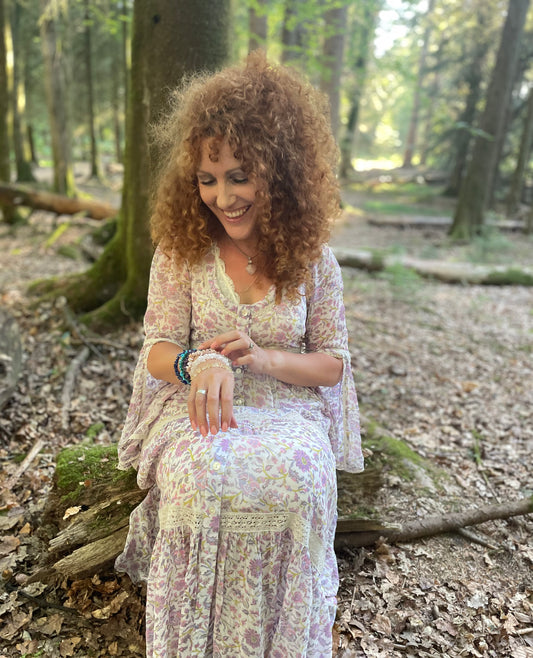 Model sitting in the woods wearing a few coloured crystal chip bracelets.